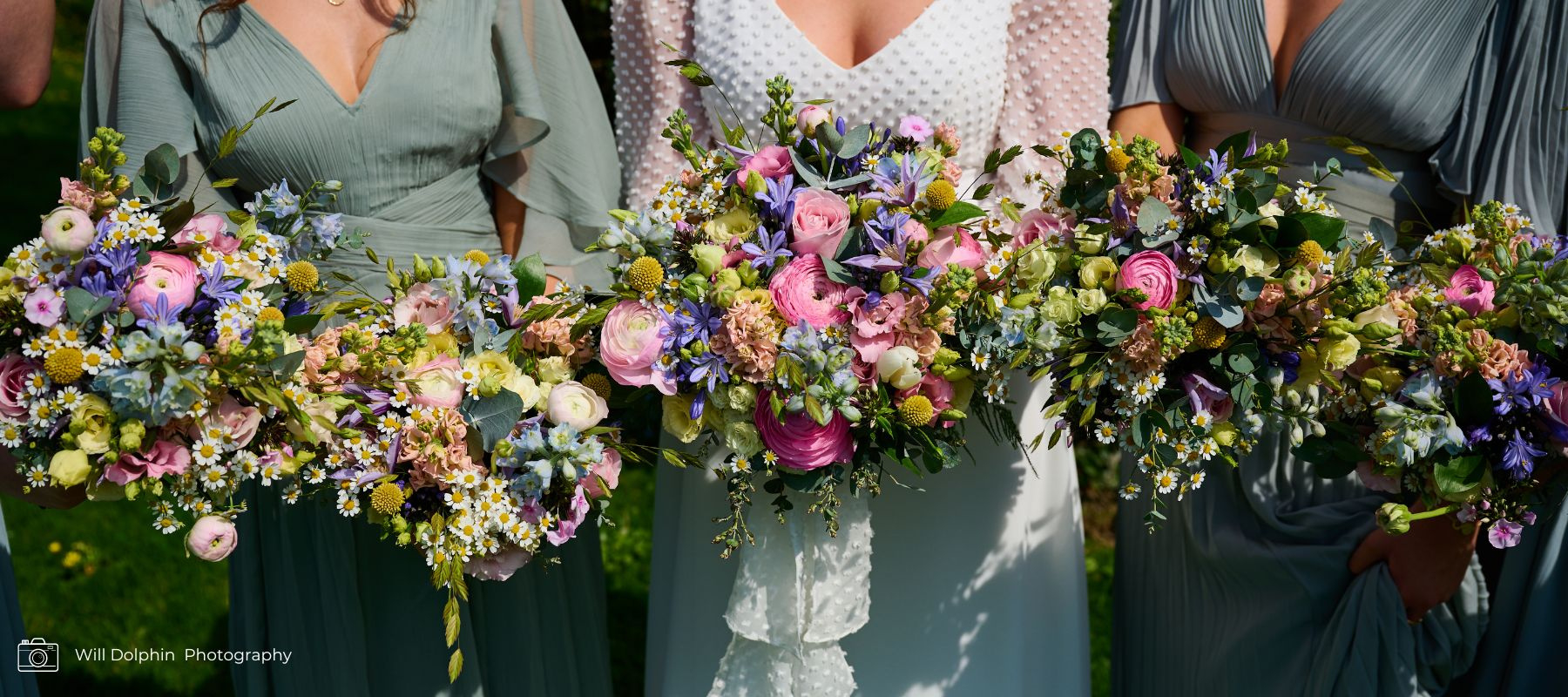 Bride and bridesmaids holding bouquets together. Spring pink, lilac and blue bouquets with pops of daisies